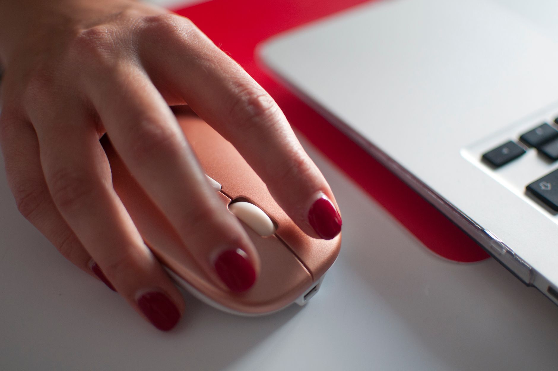 Close-up of a hand clicking a computer mouse while working at a desk