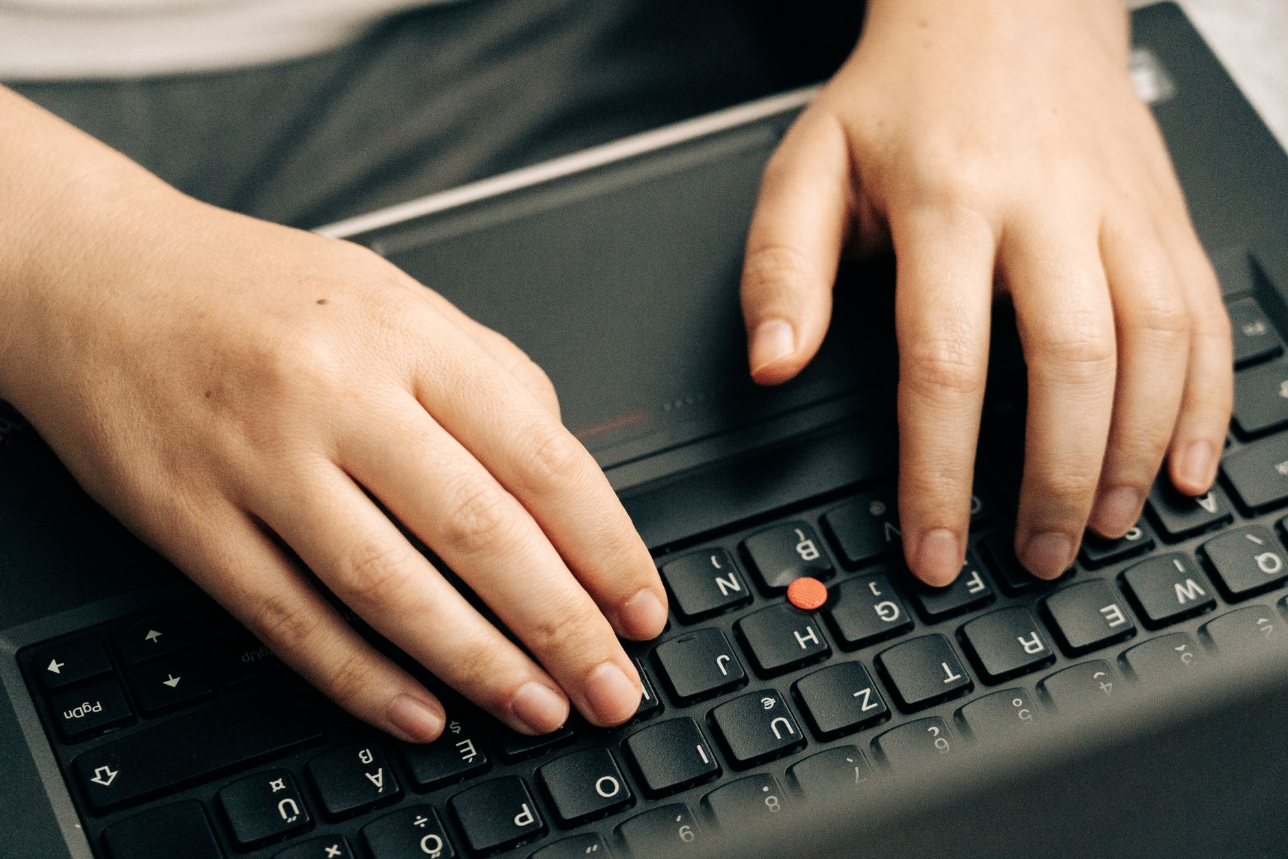 Hands typing on a laptop keyboard in soft light