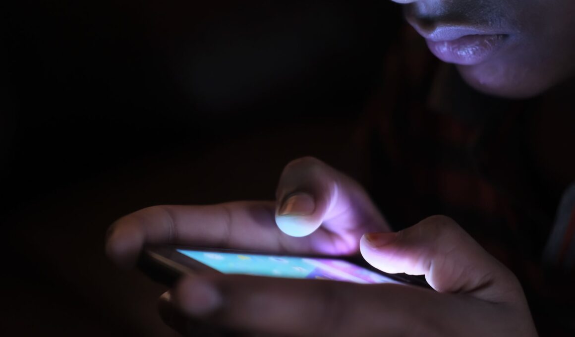 Close-up of a person using a glowing smartphone in a dark room