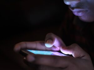 Close-up of a person using a glowing smartphone in a dark room