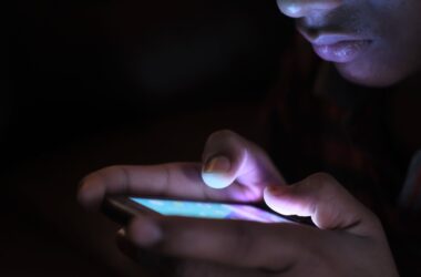 Close-up of a person using a glowing smartphone in a dark room