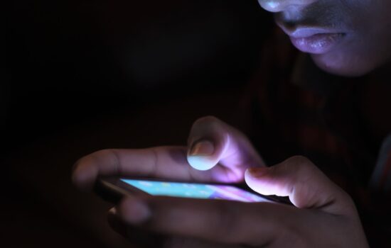 Close-up of a person using a glowing smartphone in a dark room