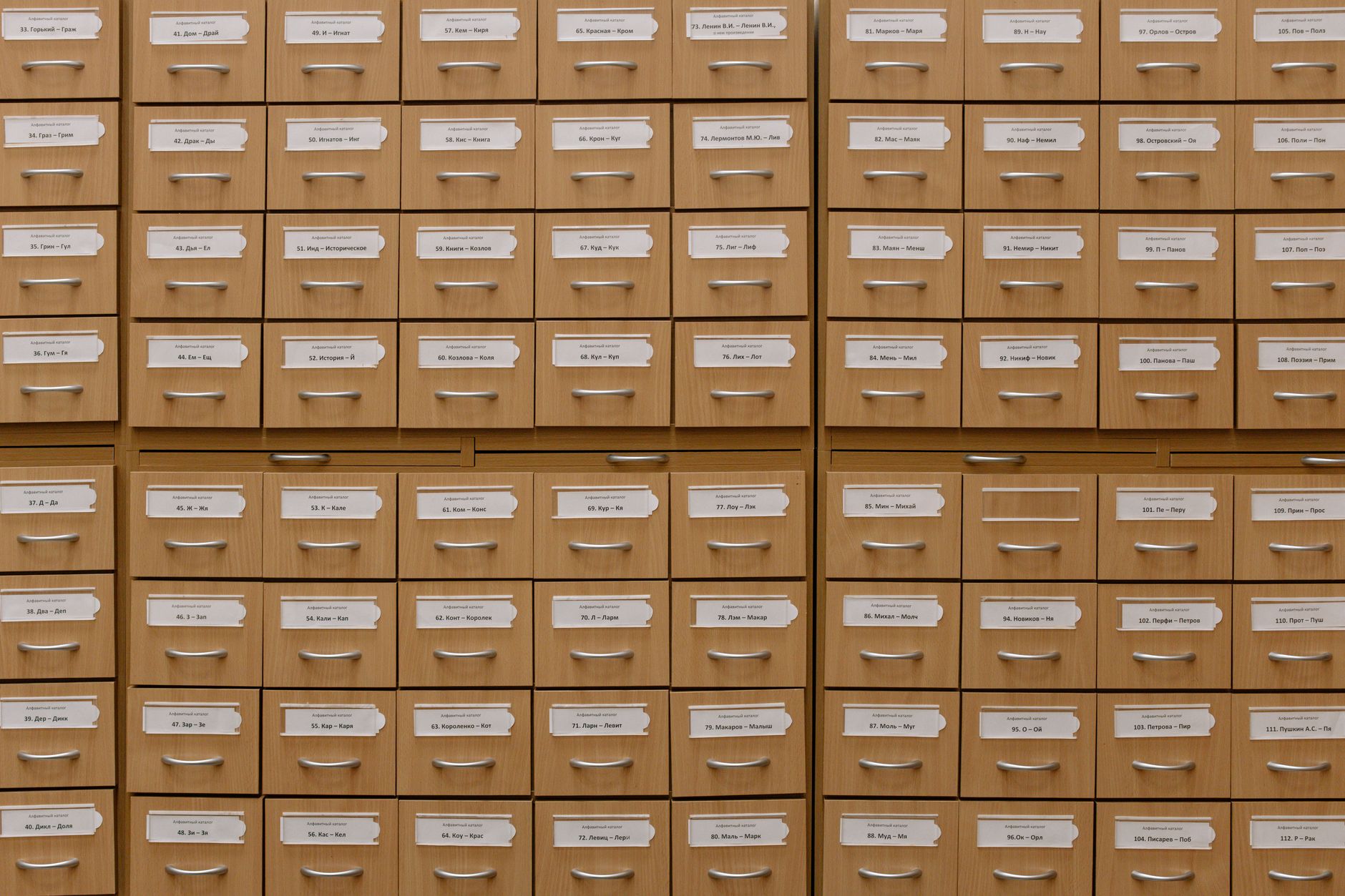 Wooden library card catalog with open drawer of index cards used for searching