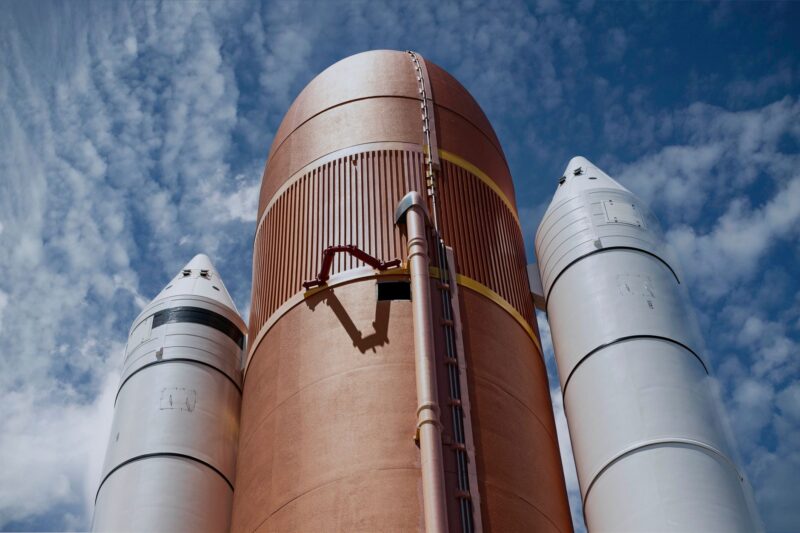 A rocket lifting off into a blue sky leaving a trail of smoke